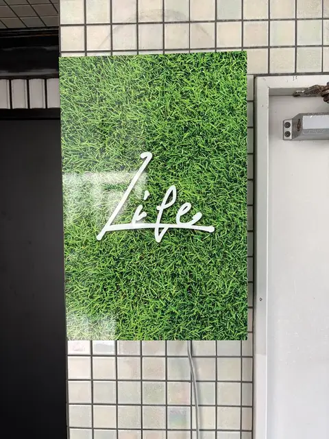 緑の壁面に白い筆記体「Life」