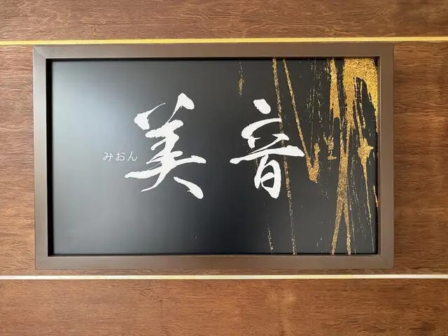 黒地に白い筆文字の「美音」