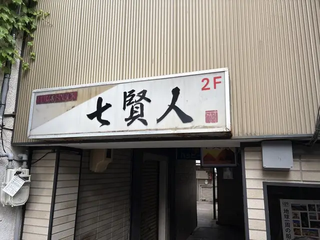 2階へ誘う白い「七賢人」看板