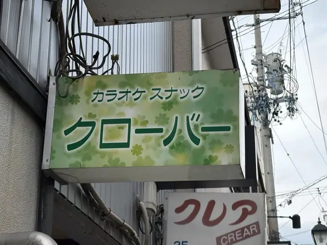 緑の柄地に大きく書かれた「カラオケ スナック クローバー」看板