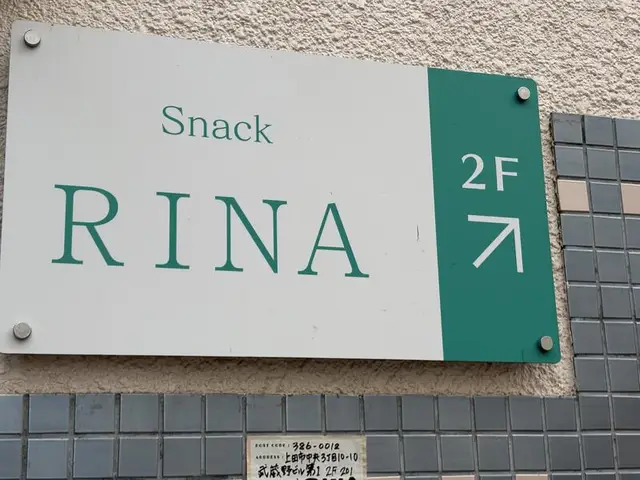 白地と緑帯で2階を示す「Snack RINA」看板