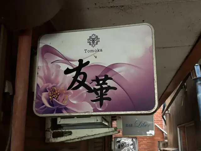紫の花背景に筆文字を重ねた「友華 Tomoka」看板