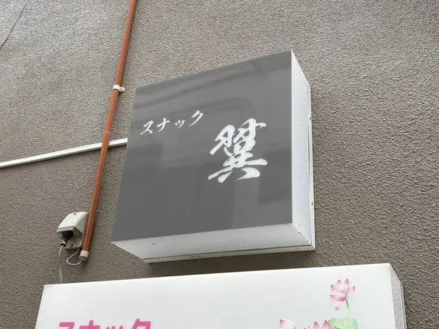 灰色の箱看板に白い筆文字を置いた「スナック 燈」看板