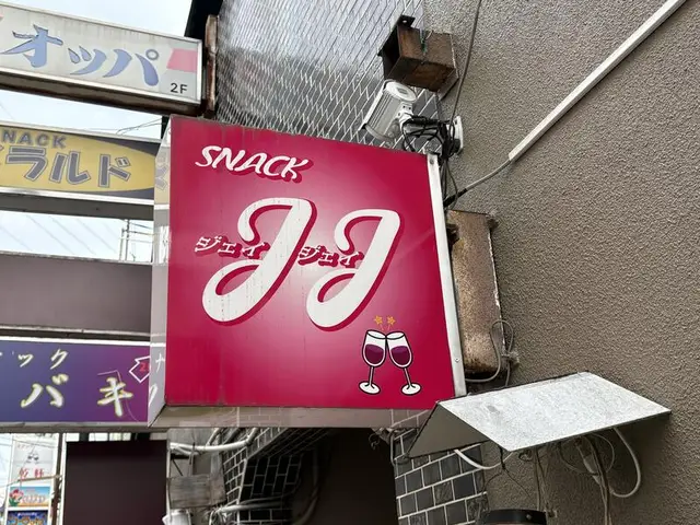 「JJ」「オッパ」「エメラルド」「ツバキ」が重なる路地の袖看板群