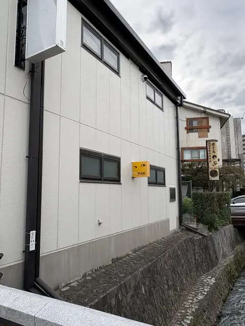 路地奥の白い外壁に小さく掛かる「熱視線」看板