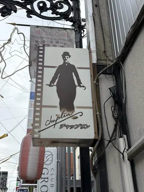 映画フィルムと人影を描いた「チャップリン」看板
