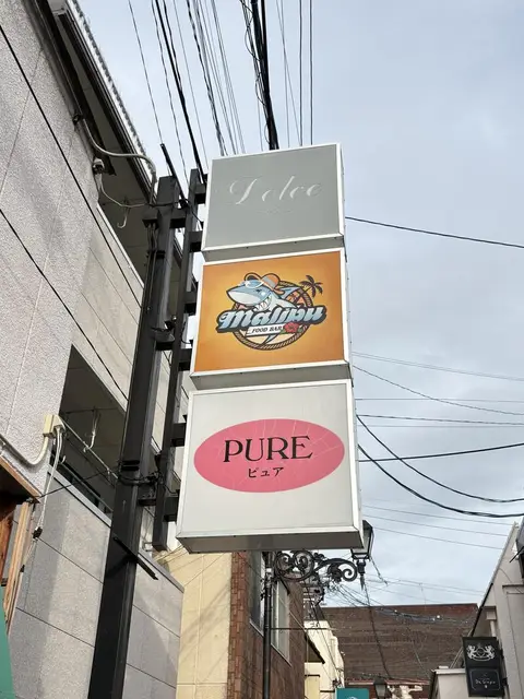 「malibu」「PURE」などが縦に重なる外壁集合看板