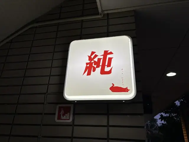 夜に灯る白地の「純」看板